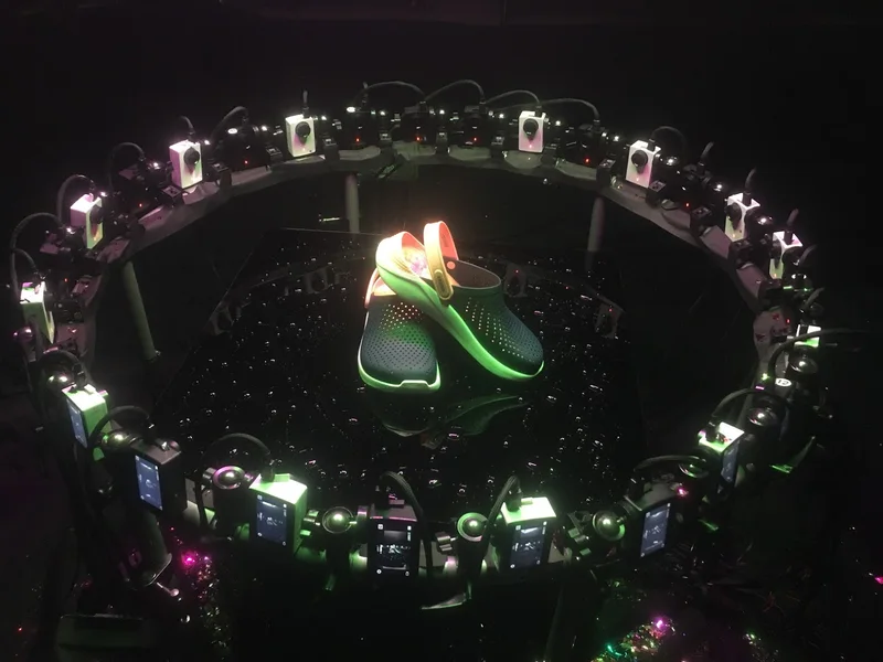 Circular camera ring capturing shoes against black background.