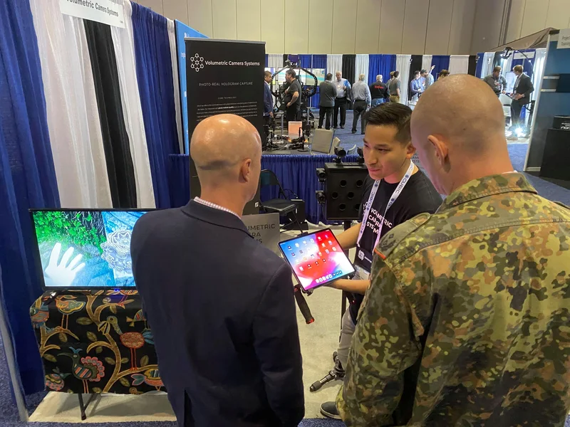 VCS staff demonstrating holographic output to two uniformed visitors.