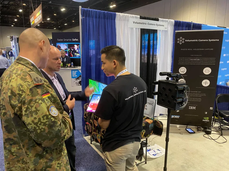 Reverse view of the VCS booth while uniformed visitors try a tablet demonstration.