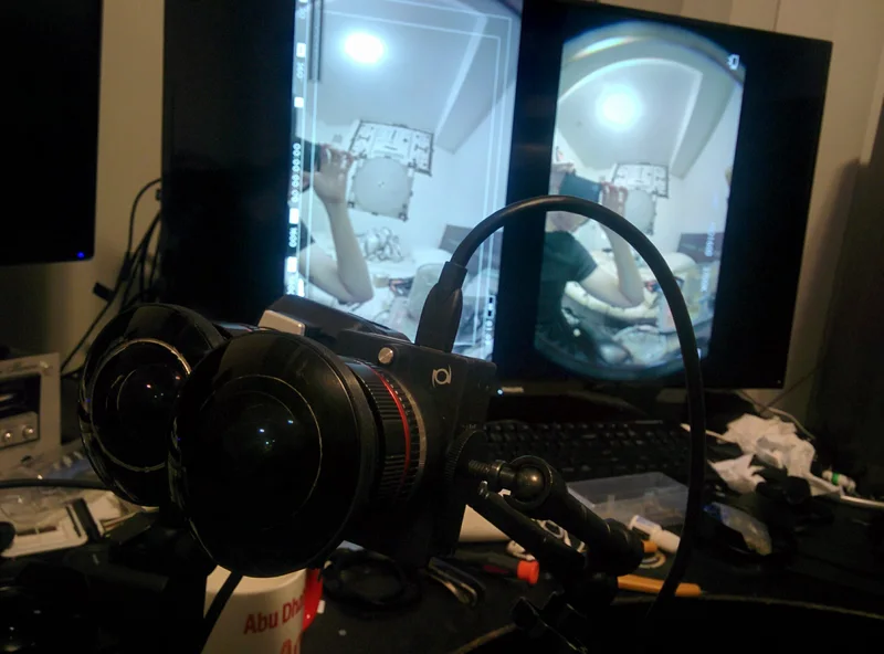 Stereo camera pair on bench in front of test monitors.