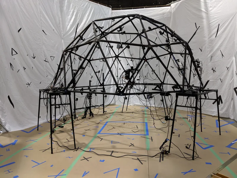 Empty portable geodesic camera dome against tracking backdrop.